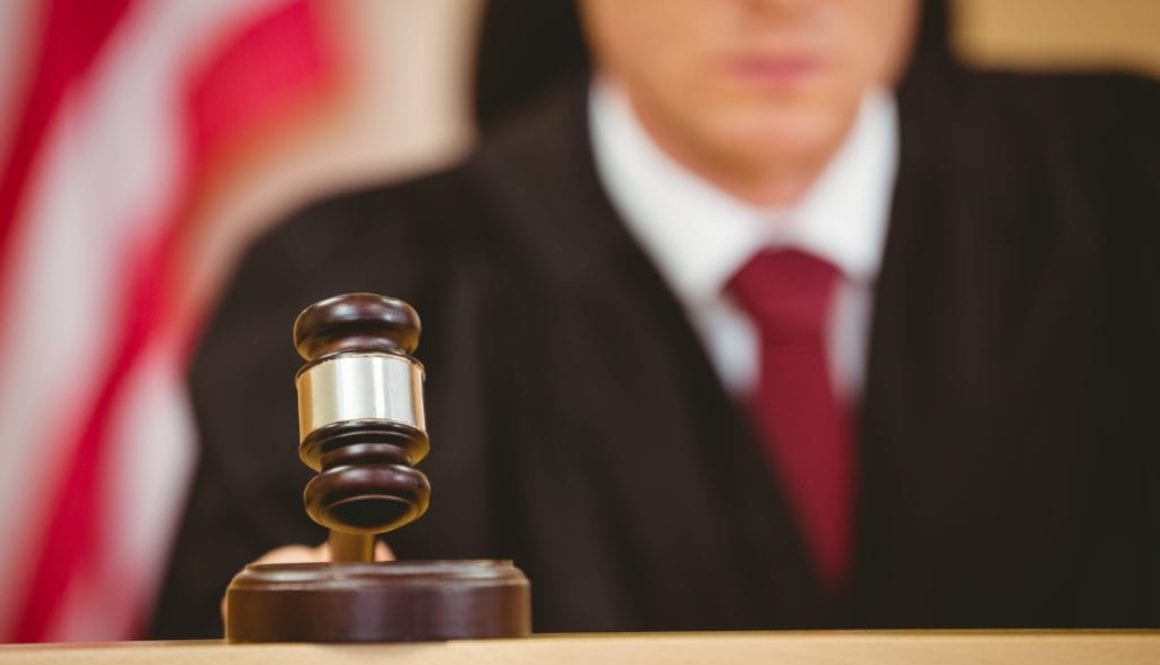 Serious judge about to bang gavel on sounding block in the court room